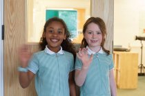 Porträt zweier Schulmädchen, die in der Grundschule winken — Stockfoto