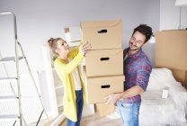 Young couple in new home with stack of cardboard boxes — Stock Photo