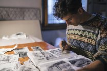 Junger Künstler zeichnet in Skizzenbuch am Schreibtisch im Atelier — Stockfoto