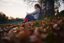 Junge Frau trainiert und nimmt Smartphone im Park mit — Stockfoto