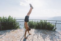 Junger Mann macht Handstand auf Aussichtsplattform, Comer See, Lombardei, Italien — Stockfoto