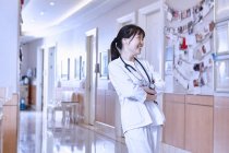 Portrait of doctor in hospital corridor looking away smiling — Stock Photo