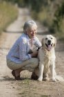 Porträt einer Seniorin, die neben Hund hockt — Stockfoto