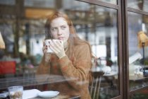 Vista attraverso la finestra della donna nella tazza della caffetteria — Foto stock