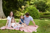 Портрет батьків середнього віку і двох дочок на пікніковому покритті в парку. — стокове фото