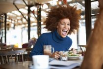 Woman laughing while dining in cafe with friend — Stock Photo