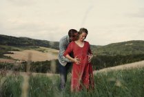 Uomo romantico con le mani sulla moglie incinta stomaco in campo — Foto stock