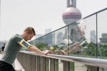 Young man runner leaning against handrail, Shanghai, China — Stock Photo