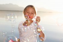 Young girl, outdoors, blowing bubbles — Stock Photo
