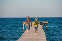 Rear view of boys running on pier — Stock Photo
