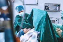Chirurghi che preparano la paziente per l'intervento in sala operatoria del reparto maternità — Foto stock