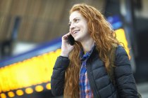 Молодая женщина разговаривает по смартфону на вокзале — стоковое фото