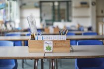 Классный стол с деревянной коробкой, полной карандашей и линейками в классе начальной школы — стоковое фото