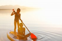 Due giovani ragazze paddle imbarco su acqua — Foto stock