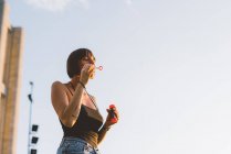 Молодая женщина, дующая пузырьками на голубое небо, Комо, Ломбардия, Италия — стоковое фото