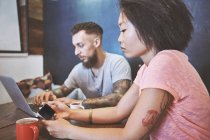 Couple hipster multi ethnique dans un café regardant smartphone et ordinateur portable, concession française de Shanghai, Shanghai, Chine — Photo de stock