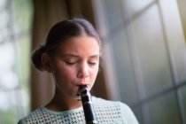 Retrato de menina tocando no clarinete dentro de casa — Fotografia de Stock