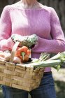Mujer con cesta de verduras de cosecha propia - foto de stock