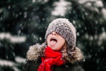 Porträt eines Mädchens, das fallenden Schnee auf der Zunge fängt — Stockfoto