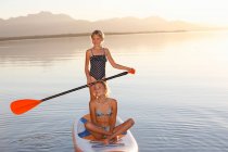 Две молодые девушки катаются на веслах по воде — стоковое фото