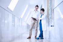 Doctors in hospital corridor looking at digital tablet — Stock Photo