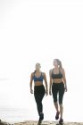 Zwei junge Frauen trainieren und gehen am Strand — Stockfoto