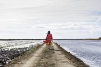 Rückansicht einer jungen Asiatin auf einem Feldweg am Meer in traditioneller Kleidung — Stockfoto