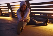 Curvaceo giovane donna formazione e toccare le dita dei piedi sul ponte pedonale — Foto stock