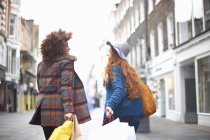 Две молодые женщины идут по улице с сумками для покупок — стоковое фото