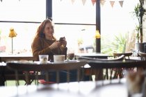 Mulher com smartphone relaxante no café — Fotografia de Stock