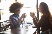 Duas jovens mulheres conversando no café — Fotografia de Stock