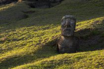 Vista lejana de estatua de piedra en colinas verdes, Isla de Pascua, Chile - foto de stock