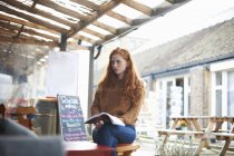 Femme au café tenant un carnet — Photo de stock