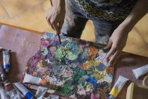 Мужчина-художник смешивает масляные краски на палитре — стоковое фото