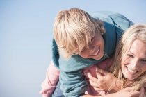 Mother carrying smiling son on back — Stock Photo