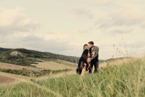 Romantic pregnant couple kissing on rural hillside — Stock Photo