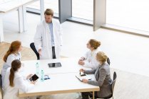 Grupo de médicos sentados à mesa, tendo reunião, vista elevada — Fotografia de Stock
