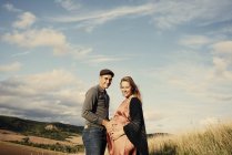 Retrato de pareja embarazada en ladera rural - foto de stock