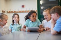 Школярки і хлопчик використовують цифровий планшет на уроці в початковій школі — стокове фото