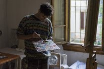 Männlicher Künstler mischt Ölfarben auf Palette im Künstleratelier — Stockfoto