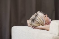 Ausgeschnittene Ansicht einer Frau, die sich auf dem Sofa entspannt, die Hände hinter dem Kopf — Stockfoto