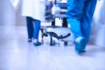 Vista traseira cortada de médicos empurrando maca no corredor — Fotografia de Stock
