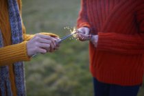 Two young women lighting sparklers — Stock Photo