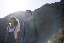 Giovane coppia di escursionisti che guarda in alto dalla valle illuminata dal sole, Las Palmas, Isole Canarie, Spagna — Foto stock