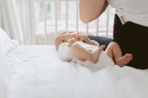 Молода жінка, сидячи на ліжку з немовляти дочки — стокове фото