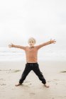 Portrait of young boy on beach with open arms — Stock Photo