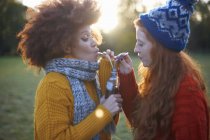 Zwei junge Frauen trinken aus Flasche mit Strohhalmen — Stockfoto