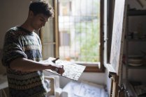 Мужчина-художник наносит масляную краску на палитру в мастерской художника — стоковое фото