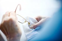 Senior woman cleaning eyeglasses with cloth, mid section — Stock Photo