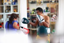 Mature woman practicing boxing with male trainer in gym — Stock Photo
